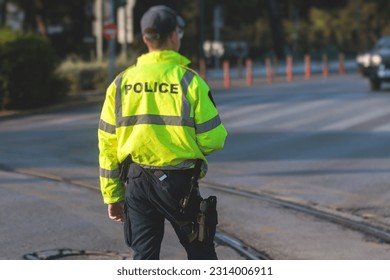 Inspector of traffic police highway patrol regulates the movement of transport in the center of european city, in green yellow vest jacket with a sign 