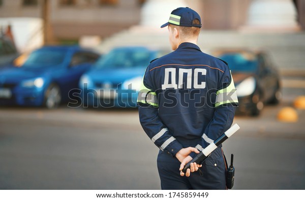 Inspector of traffic police in uniform with sign\
DPS (inscription - Department of traffic police) on duty . Traffic\
police Inspector enforcing traffic safety compliance on roads and\
highways