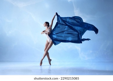 Inspiration, aesthetic. Beautiful ballerina wearing beige bodysuits emotional dancing with fabric silk over blue background. Ballet with silk. The art, artist, movement, action and motion concept - Powered by Shutterstock