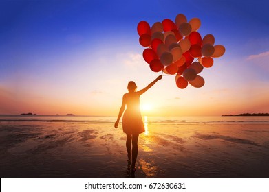 inspiration, joy and happiness concept, silhouette of woman with many flying balloons on the beach