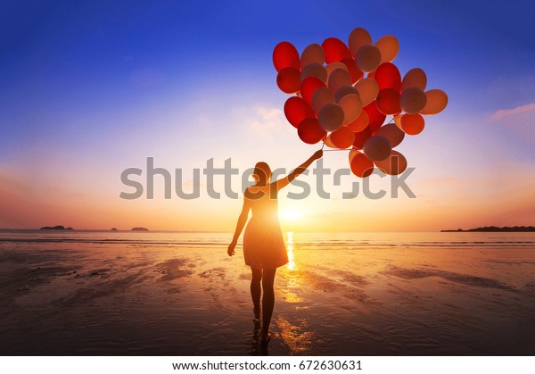 inspiration, joy and happiness concept, silhouette of woman with many flying balloons on the beach