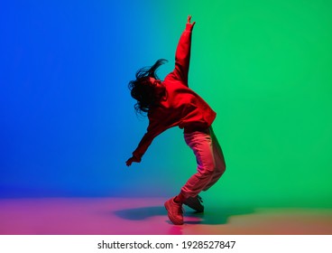 Inspiración. Niña deportiva elegante bailando hip-hop con ropa elegante sobre fondo colorido en la sala de baile a la luz de los neones. Cultura juvenil, movimiento, estilo y moda, acción. Brillo moderno