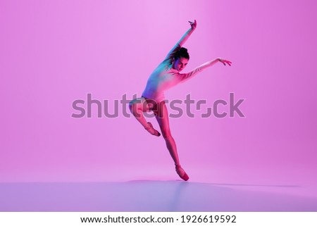 Inspiration. Young and graceful ballet dancer on pink studio background in neon light. Art, motion, action, flexibility, inspiration concept. Flexible caucasian ballet dancer, moves in glow.