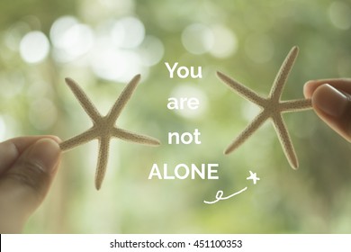 Inspirational quote "you are not alone" on blurred background