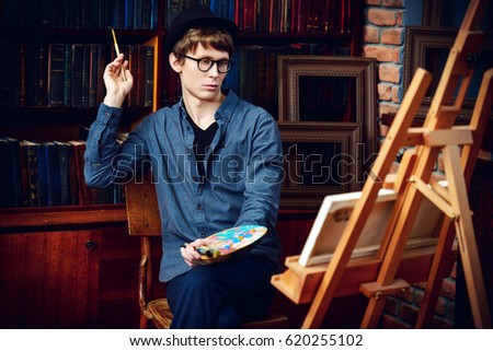 Inspired artist man draws a picture in the workshop. Arts and painting.