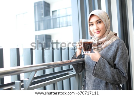Inspired with cup of fresh coffee. Thoughtful young woman in smart casual wear holding coffee cup and looking away or happy young woman with cup of tea or coffee at home