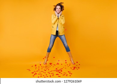 Inspired girl in bright autumn attire jumping in studio. Graceful brunette female model dancing in valentine's day.