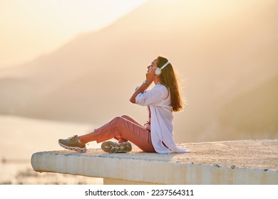 Inspired happy serene female with closed eyes enjoying of listening calm music with beautiful view at sunset time. Relief stress and healthy minds  - Powered by Shutterstock
