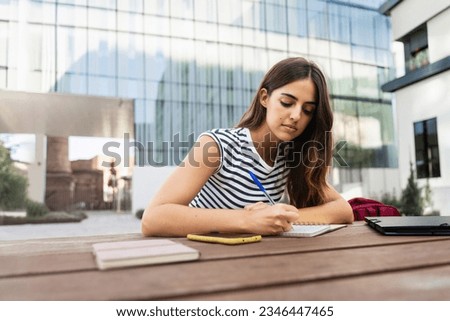 Inspired hispanic woman studying and writing notes at the University - Student girl thinking and working on project 
