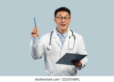 Inspired Middle Aged Chinese Male Doctor In White Coat And Glasses With Tablet Rising Pen Up, Isolated On Blue Background, Studio. Got Idea, Great Ad And Offer, Solution For Treatment, Health Care