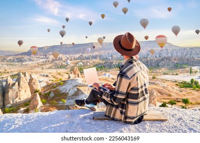 Inspired travel blogger guy working remotely and enjoying air balloons landscape