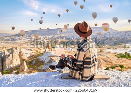 Inspired travel blogger guy working remotely and enjoying air balloons landscape