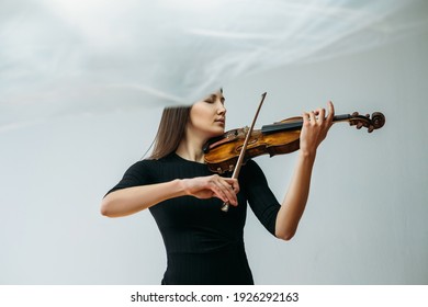 Inspired violinist woman. Online concert. Self isolation. Professional artist. Calm lady playing violin closed eyes with transparent plastic film under head isolated neutral.
