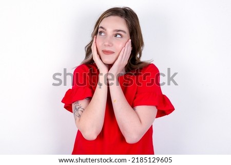 Inspired young caucasian woman wearing red T-shirt over white background looking at copyspace having thoughts about future events