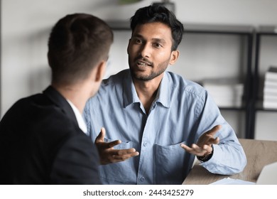 Inspired young Indian entrepreneur man talking to business partner, consulting financial specialist, legal expert at office workplace. Project manager explaining job task to colleague - Powered by Shutterstock