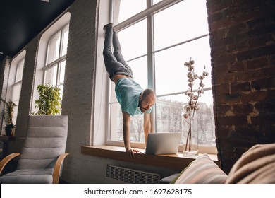 Inspired. Young Man Doing Yoga At Home While Being Quarantine And Freelance Online Working. Remote Office, Isolated. Concept Of Healthy Lifestyle, Wellness, Being Safe While Coronavirus Pandemic.