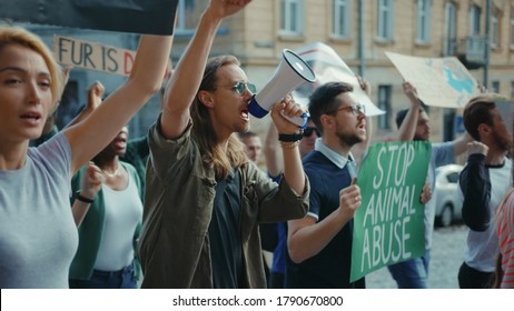 Inspiring Man Leader Agitating Crowd With Loudspeaker Outdoors. Multi-ethnic Active Urban Youth Protesting For Animal Rights And Safe Ecology In Public Demonstration.