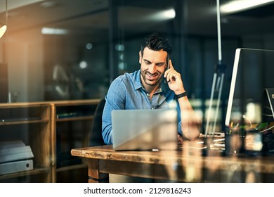 Inspiring productivity with a wealth of technology. Shot of a young businessman talking on his phone and using a laptop during a late night at work. - Shutterstock ID 2129816243