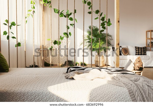 Inspiring rope and ivy decorative room\
divider next to elegant bed in original\
apartment