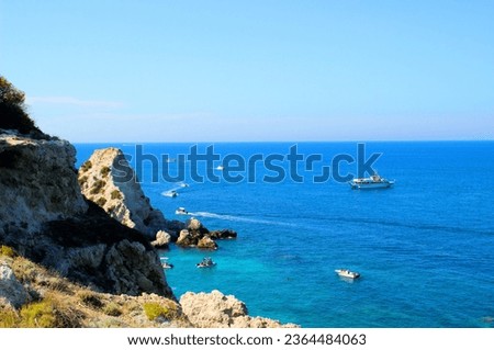 Inspiring view from Tremiti Islands (Isole Tremiti) at rocky slopes in the left foreground opening to a sublime vision of extensive, only slightly perturbed Adriatic Sea, with motorboats and ships