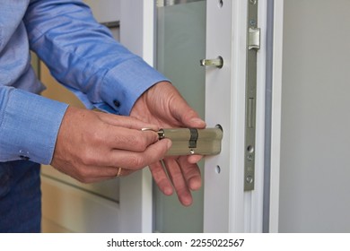 install a cylinder lock in a plastic door,a man with a key installs the lock cylinder in the door, assembling the lock into the plastic door