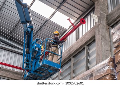 Install fire sprinkler system. In the industrial plant, pipe assembly, red fire pipe, fire protection contractors Using Scissor Lift High work - Shutterstock ID 1032702601