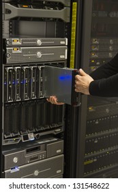 Install or remove a server in a blade chassis in a rack. Shot in a data center.