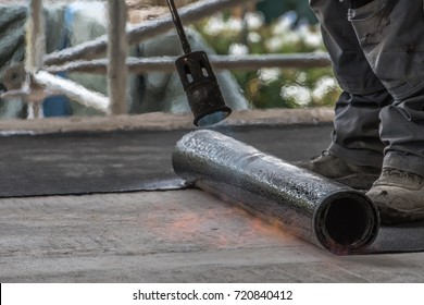 Installation by heating and melting of bitumen rolls by torch to flame while sealing the substrate against ascending moisture. Professional installation of the waterproofing on the concrete foundation