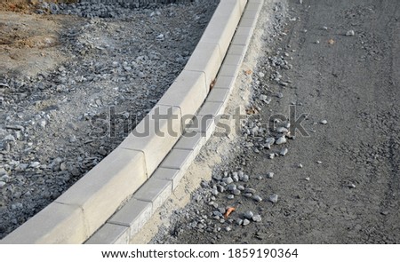 installation of concrete curb into concrete. in the space of the road, which so far has only a concrete base before laying the asphalt layer and rolling.