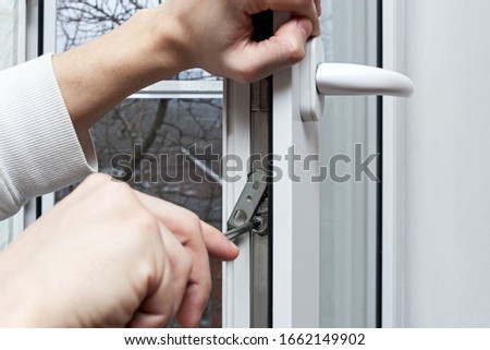 Installation, configuration and maintenance of plastic windows made of PVC. The handyman opened and adjusts the plastic window in the house. Adjustment of the lock mechanism with a screwdriver.