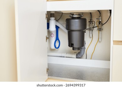 The installation of a functional garbage disposal unit beneath the kitchen sink showcases essential plumbing setup.