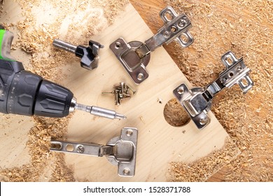 Installation of furniture hinges in chipboard. Small carpentry work in the workshop. light background. - Shutterstock ID 1528371788