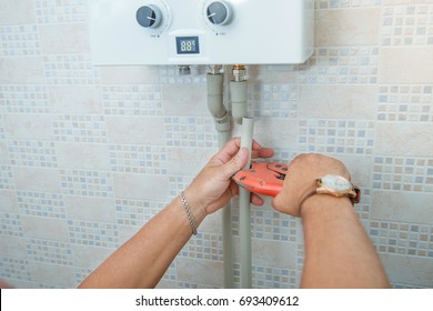 Installation Of Gas Boiler. Man Is Installing Plastic Pipes In The Kitchen. Plumbing