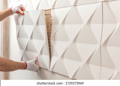 Installation of gypsum 3D panel. A worker is attaching the gypsum tile to the wall.