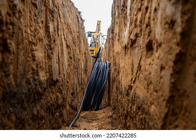 Installation of HDPE pipes in the trench. The process of laying of engineering systems water supply. Black plastic pipes underground. - Shutterstock ID 2207422285
