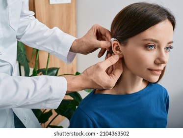 Installation hearing aid on woman's ear at hearing clinic, close-up, side view. Deafness treatment, hearing solutions - Shutterstock ID 2104363502