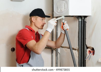 Installation Of Home Heating. Worker Attaches The Pipe To The Gas Boiler.