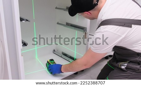 Installation of kitchen accessories using a construction laser. Professional worker. 