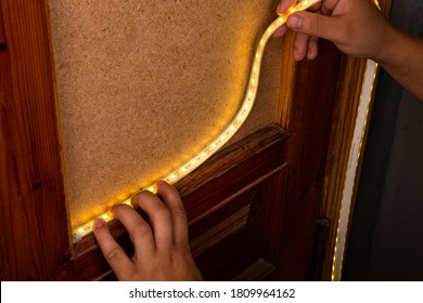 installation of LED strip with warm yellow light on the door for decorative lighting.