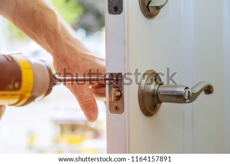 Installation locked interior door knobs, close-up woodworker hands install lock.