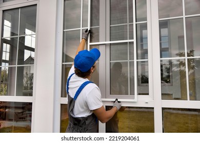 Installation Of A Mosquito Net On A Large Window Outside A Modern Building. An Experienced Installer Installs A Protective Net Against Insects On A Plastic Window