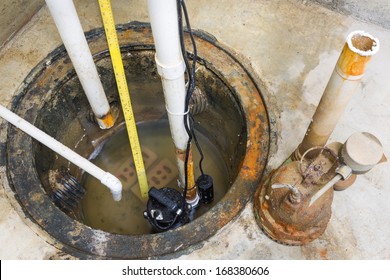Installation of a new sump pump and the removal of the old obsolete rusty one with a high angle view of the pumps, pit and pipes
