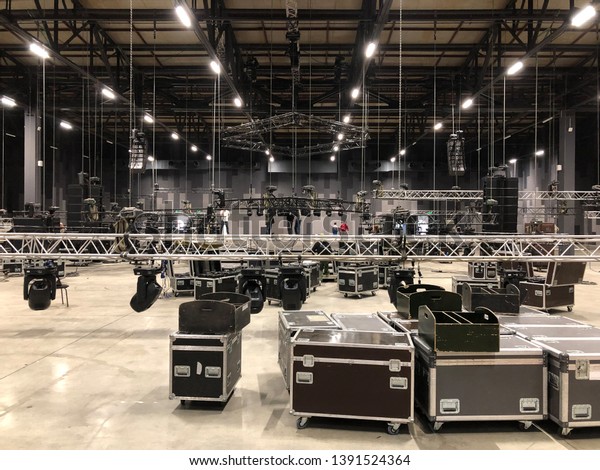 Installation of\
professional sound, light, video and stage equipment for a concert.\
Stage lighting equipment is clamped on a truss for lifting. Flight\
cases with cables.