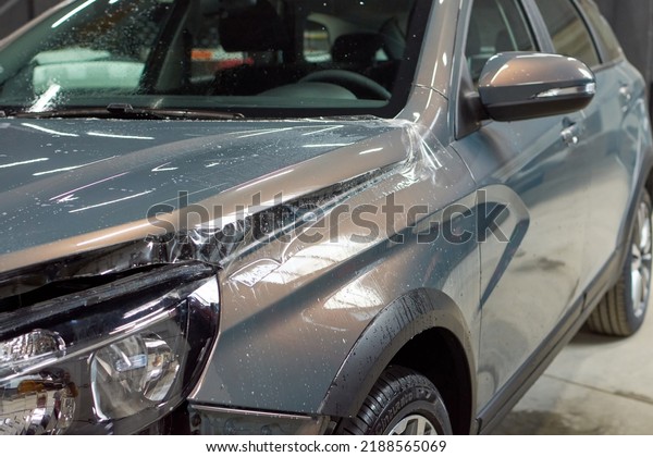 Installation of a protective paint and varnish\
transparent film on the car. PPF polyurethane film to protect the\
car paint from stones, marks and scratches. Chelyabinsk, Russia,\
April 17, 2021