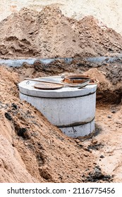 Installation Of A Reinforced Concrete Well For Water Supply And Sewerage At The Construction Site. Well Rings With Cast Iron Hatch And Construction Tool