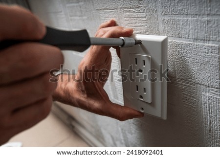 Installation or repair of electrical outlet socket box within the wall. Hands of serviceman or repairman fixing with Type B Duplex Receptacle - American socket with grounding 