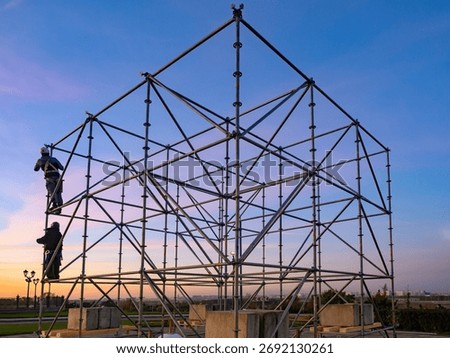 Installation scaffolding and platforms. Erection temporary metal structure outdoors. Construction scaffolding for concerts. Installation of metal scaffolding. Platform under construction at sunset.