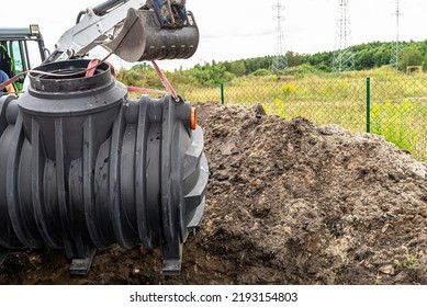 Installation Of A Single-chamber Home Sewage Treatment Plant, The Excavator Raises The Tank.