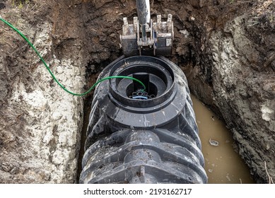 Installation Of A Single-chamber Home Sewage Treatment Plant, The Excavator Raises The Tank.