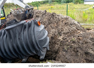 Installation Of A Single-chamber Home Sewage Treatment Plant, The Excavator Raises The Tank.